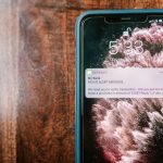 Close-up de um smartphone exibindo uma notificação de alerta sobre fraude sobre uma superfície de madeira