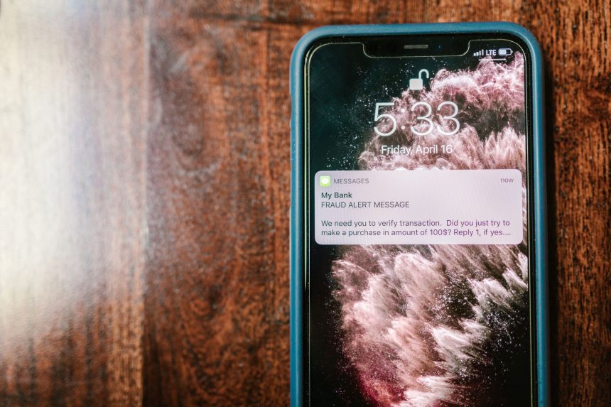 Close-up de um smartphone exibindo uma notificação de alerta sobre fraude sobre uma superfície de madeira