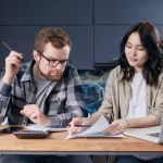 Casal calcula contas e organiza as finanças domésticas sentado à mesa em casa.