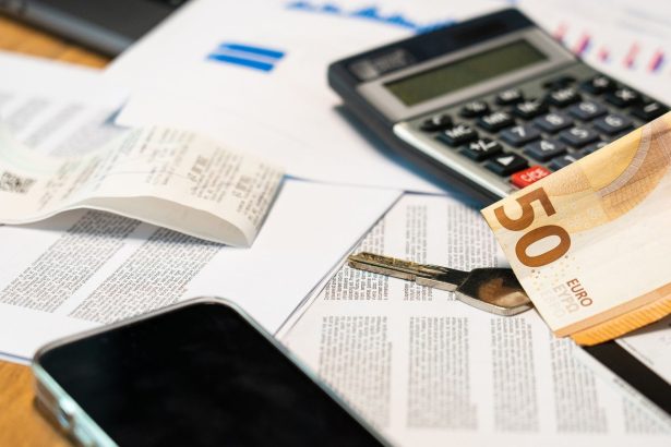 Documentos financeiros ao lado de uma calculadora, smartphone, nota de euro e chave, representando o controle e a gestão de despesas.