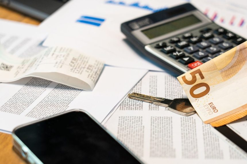 Documentos financeiros ao lado de uma calculadora, smartphone, nota de euro e chave, representando o controle e a gestão de despesas.