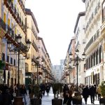 Rua de pedestres movimentada em Zaragoza, na Espanha, com pessoas circulando entre edifícios e estabelecimentos comerciais.
